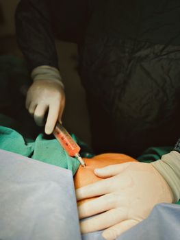 Close-up of a surgeon injecting fluid during a medical procedure in an operating room.