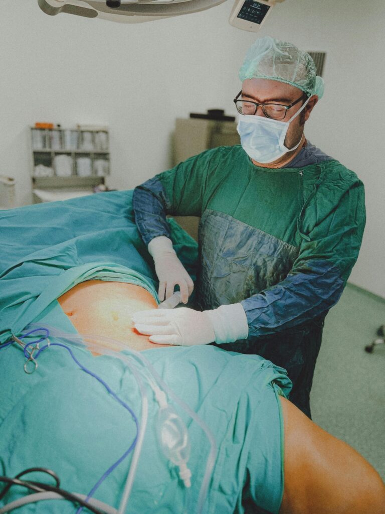 Surgeon in a hospital operating room wearing scrubs and mask preparing for surgery.